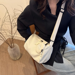 Creamy white cylindrical crossbody bag with adjustable wide strap and mini coin pouch