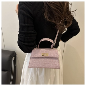 Detail of pink glitter crossbody bag featuring a gold metal twist lock and textured finish
