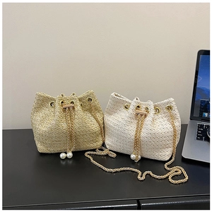 Detail of woven bucket bags with golden chain drawstrings and large pearl pendants