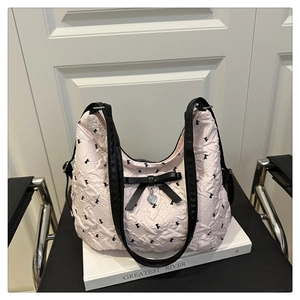 Détail du sac matelassé rose avec nœuds noirs et pendentif en forme de cœur en métal