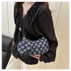 Close-up of denim blue checkered crescent bag with fringe detail and round coin pouch