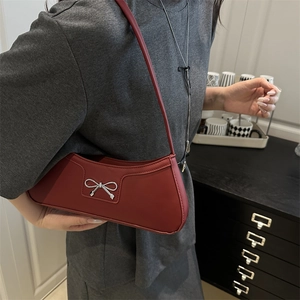Minimalist burgundy crescent underarm bag with silver metallic bow shown on model