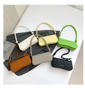 Flat lay of minimalist leather baguette bags in six vibrant colors with gold lettering