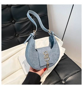 Detail of light blue crescent hobo bag featuring gold S-logo and metallic tassel decor