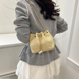 Elegant beige straw bucket bag with gold chain strap and pearl drawstring details