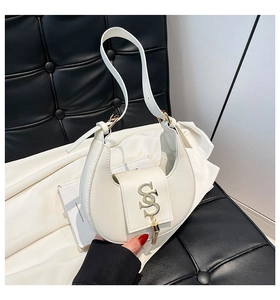Detail of white crescent bag showing golden S logo and elegant tassel on leather