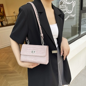 Pink crossbody bag with crocodile texture and silver chain strap worn by a model