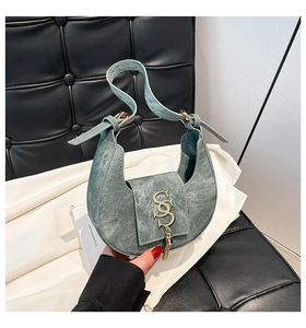 Detail of light green crescent bag with denim texture and metallic logo charm