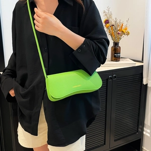 Vibrant lime green leather underarm bag with a wavy base worn by a model in casual black outfit