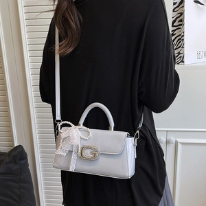 Detail of grey handbag with crystal G buckle and lace pearl bow accessory on strap