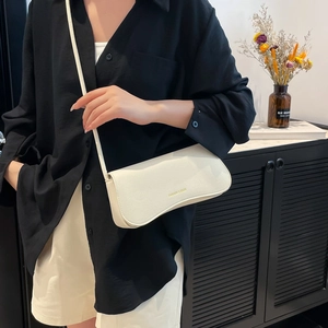 Minimalist white litchi leather crossbody bag with gold lettering shown on model