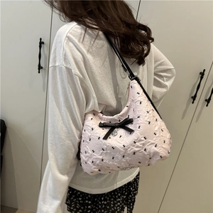 Sac à épaule matelassé rose avec nœuds noirs et motifs lapins porté par un mannequin