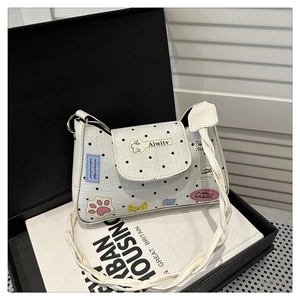 Dettaglio della borsa bianca a pois con toppe cartoon e tracolla con nodo
