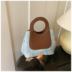 Detail of light blue denim bucket bag with sparkling rhinestones and brown leather handle