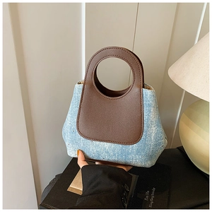 Detail of blue denim bucket bag with sparkling rhinestones and brown leather handles