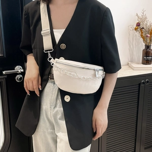 Sac selle blanc cassé avec chaîne argentée et large bandoulière porté par un mannequin