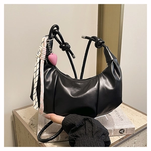 Detail of black pleated moon bag with knot handle and pink heart tassel decoration