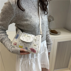 Borsa a tracolla bianca a pois con ricami colorati e cinturino sottile indossata da modella