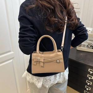 Chic beige square crossbody bag with bow detail worn by a model in elegant indoor setting