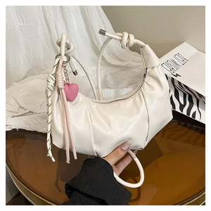 Detail of off-white ruched dumpling bag with knot handle and pink heart charm