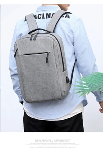 Detail of grey minimalist backpack showing external USB charging port and fabric texture
