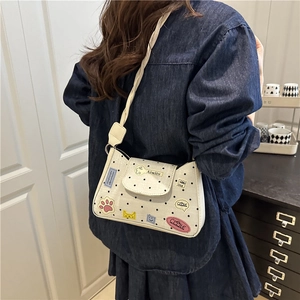 Elegante borsa a tracolla bianca a pois con toppe a fumetti indossata in un contesto lifestyle