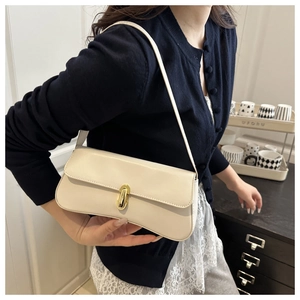 Detail of a cream baguette bag with a signature gold oval twist lock and sleek leather finish