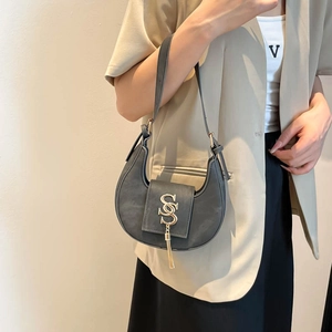 Chic dark gray matte crescent bag with gold S-buckle and tassel on a female model