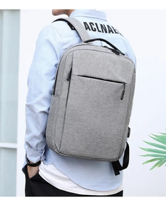 Detailed view of grey backpack showing external USB charging port and oxford fabric texture