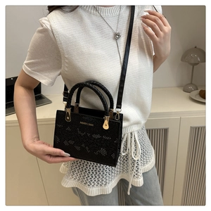 Details der schwarzen Handtasche mit Schlangenprägung, Goldbeschlägen und Webgriff