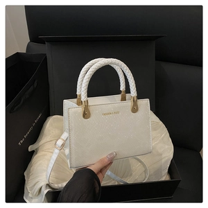 Detail der weißen Handtasche mit Schlangenmuster und Goldbeschlägen in Geschenkbox