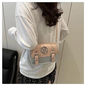 Detailed view of pink and grey square crossbody bag with metallic M logo on model