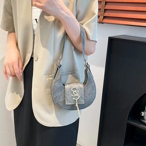 Chic gray crescent shoulder bag featuring metal logo and tassel on high-end leather