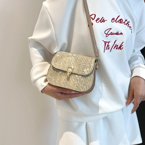 Beige straw woven crossbody bag featuring floral embroidery and slim brown shoulder strap
