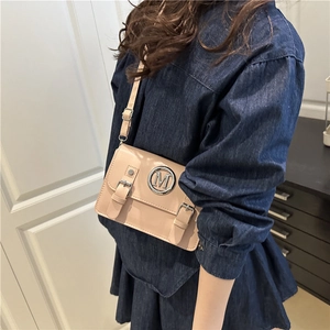 Beige rectangular crossbody bag with flap cover and metal M logo on minimalist strap