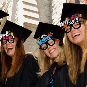Three students wearing graduation caps and inspirational decorative party glasses frames