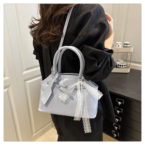 Sac bandoulière bleu clair avec nœud en dentelle porté à l'épaule pour l'échelle