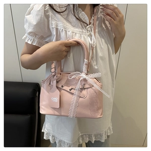 Detail of pink leather handbag with white lace bow and decorative metal strap buckle