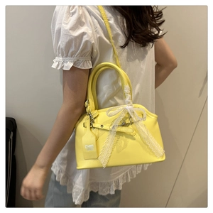 Détail d'un sac coquillage jaune avec nœud en dentelle blanche et étiquette chic bag