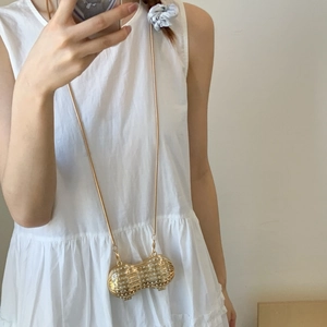 Pochette de soirée en forme d'arachide dorée avec strass et chaîne en métal sur modèle