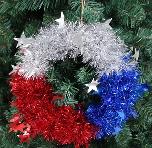 Detalle de corona patriótica de oropel con estrellas rojas plateadas azules en rama