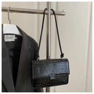 Detail of glossy black crocodile-pattern faux leather bag with silver square twist lock