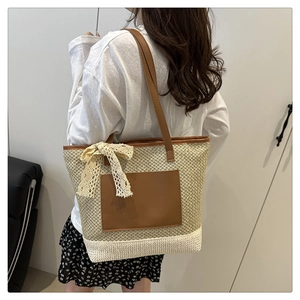 Close-up of woven straw bucket bag featuring a brown front pocket and lace bow detail