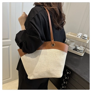 Detail of cream woven tote bag with brown leather straps shown on model in a home setting
