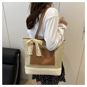 Detail of straw woven bucket bag with leather pocket and delicate lace bow decoration