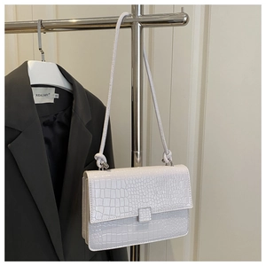 Detail of white crocodile embossed texture on PU leather square shoulder bag with metal buckle