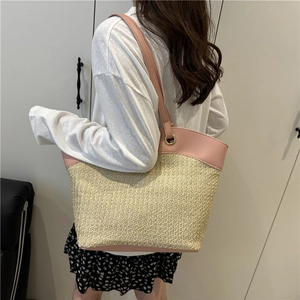 Fashionable straw tote bag with pink leather straps shown on model for shoulder style