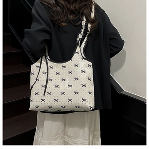 Detail of canvas tote bag with black bow patterns and ruffled shoulder straps
