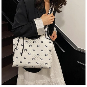Polka dot canvas tote bag with bow print worn over the shoulder by a model on stairs