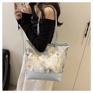 Detailed embroidery of floral patterns on canvas and light blue leather tote bag